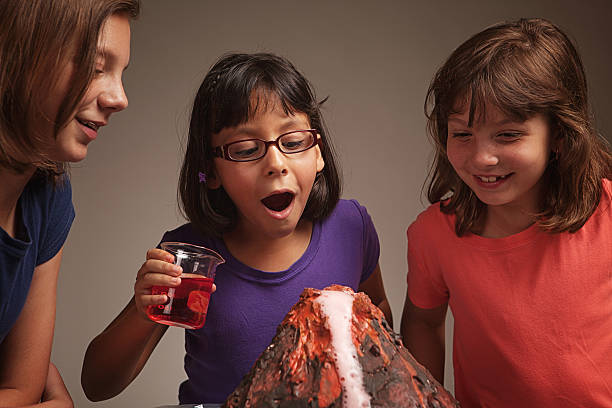Little girls make their volcano science project erupt.