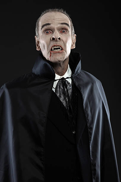 istock Dracula with black cape showing his scary teeth. Vamp fangs. 460812881