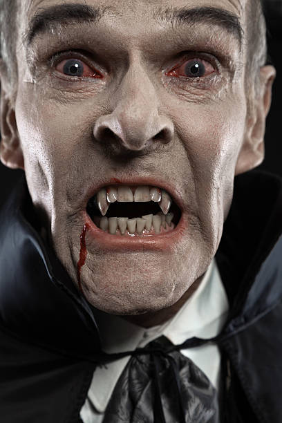 istock Dracula with black cape showing his scary teeth. Vamp fangs. 460812937