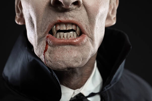 istock Close-up of dracula with black cape showing his scary teeth. 460812961