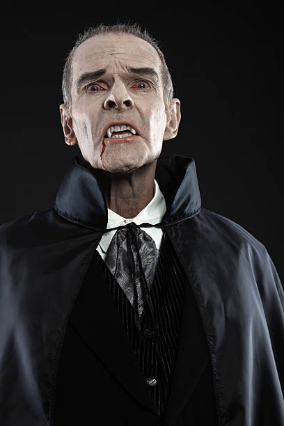 istock Dracula with black cape showing his scary teeth. Vamp fangs. 460813467