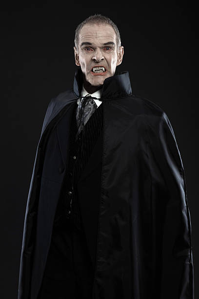 istock Dracula with black cape showing his scary teeth. Vamp fangs. 460813539