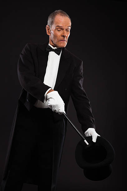 istock Magician with black suit and hat holding a magic stick. 460818835