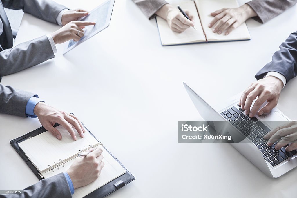 Four business people during a meeting, hands only Four business people around a table and during a business meeting, hands only Suit Stock Photo