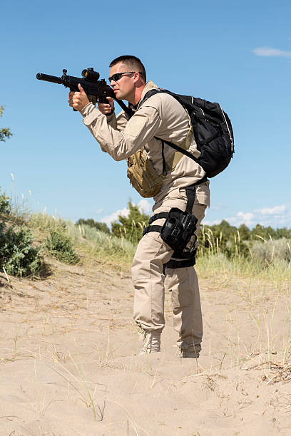 istock Modern soldier taking aim on patrol in desert landscape 460833113