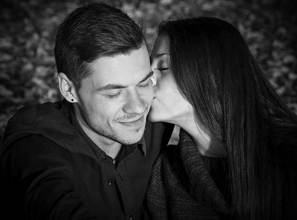 she kisses his cheek eyes closed black and white