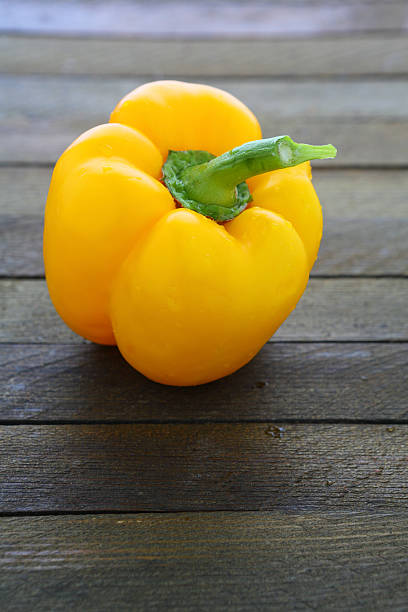 istock round yellow pepper on wooden surface 460841767