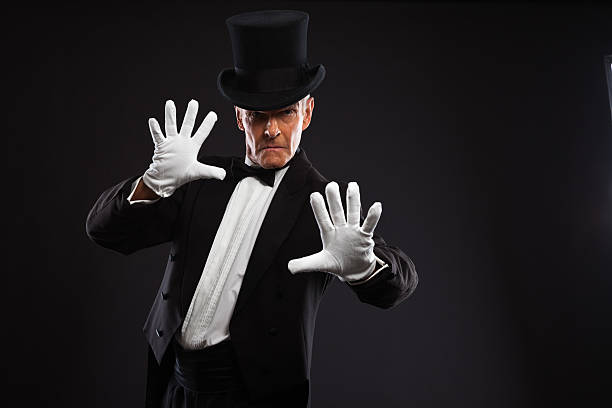 istock A magician, dressed in black and white, making a gesture 460842177