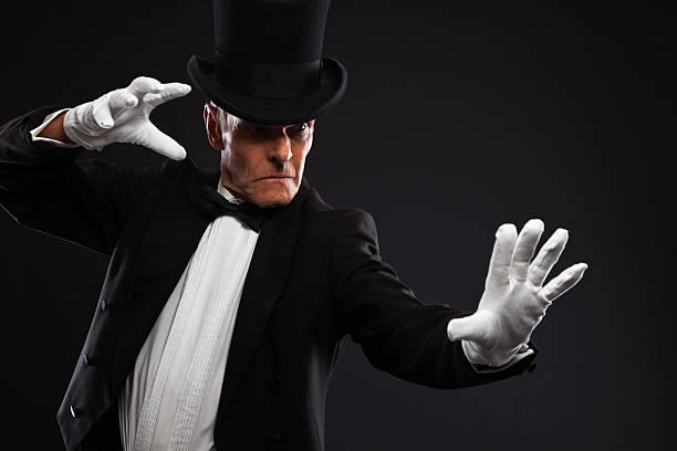 istock Magician making mysterious gestures. Wearing black suit and hat. 460842195