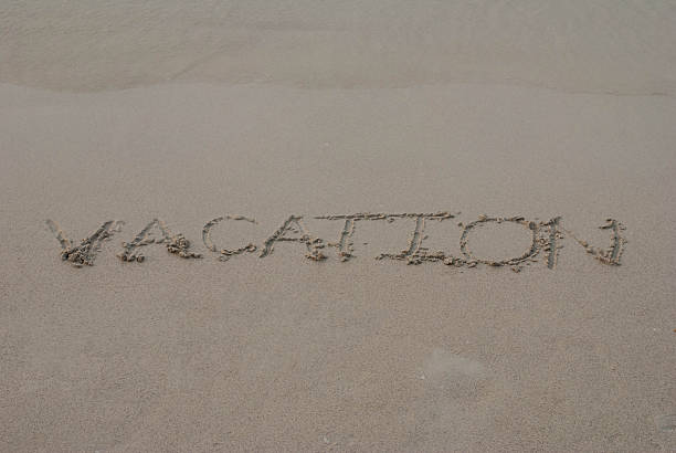 istock vacation written in a sandy tropical beach 460842947