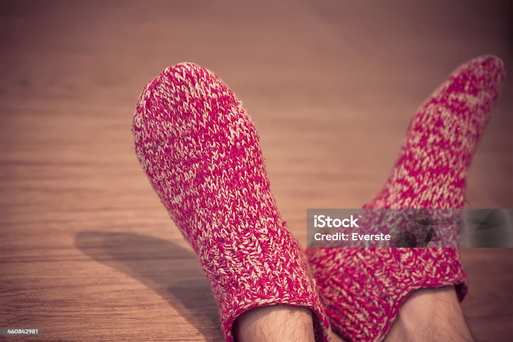 Man Legs in red Wool Socks male knitted clothes winter Man Legs in red Wool Socks male knitted clothes winter handmade accessories home comfort concept on wooden background trendy colors Slipper Stock Photo