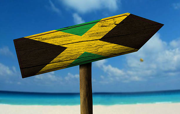 bandeira da jamaica, com uma placa de madeira no fundo de praia - jamaican culture imagens e fotografias de stock