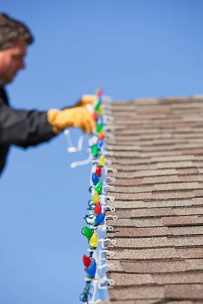 istock Man Installing LED Christmas Lights on House Roof 460845701