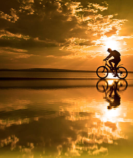 istock silhouette of cyclist at sunset with a blurred reflection 460852209