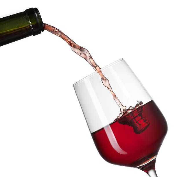 istock Red wine pouring into glass with splash isolated on white 460870407