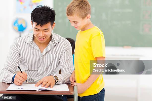 Photo libre de droit de Jeune Mâle Enseignant Donner Une Note À Lécole De Garçon De Travail banque d'images et plus d'images libres de droit de Donner une note