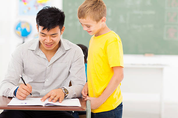 jovem professor do sexo masculino menino de escola o trabalho de nivelamento - grading teacher desk writing - fotografias e filmes do acervo