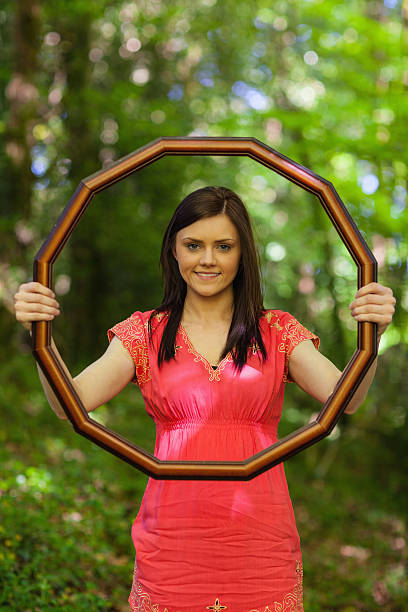 istock Happy brunette holding a picture frame and smiling at camera 460921155