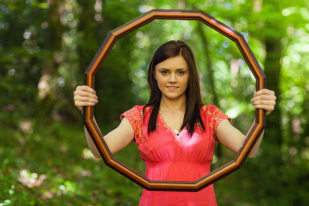 istock Pretty brunette holding a picture frame and smiling at camera 460921163