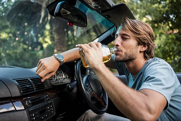 istock Man slumped in the car drinking bottle of whiskey 460930429