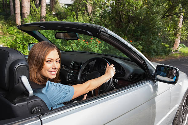istock Brunette driving a convertible and looking at camera 460939447