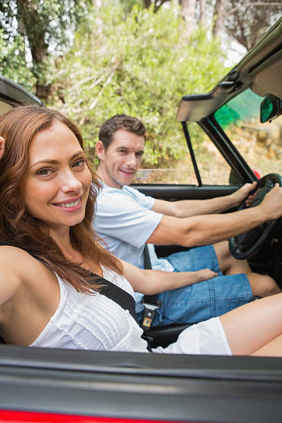 istock Attractive couple driving a red convertible smiling at camera 460969589