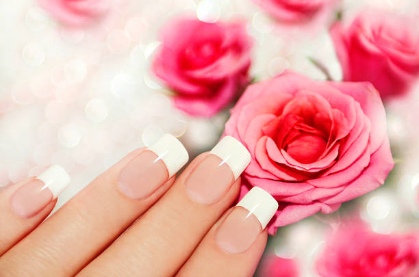 istock French manicured nails next to pink roses 461041537