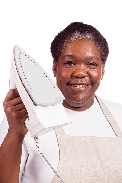A mature woman shows off her electric iron with a smile.