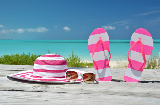 Hat, sunglasses and flip-flops against ocean. Exuma, BahamasTwo pairs of flip-flops against ocean. Exuma, Bahamas