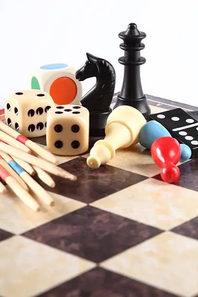 Detail of board games, pawns, chessmen, mikado and dices on chess board.
