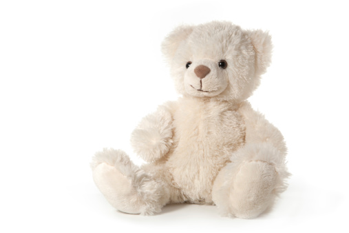 Stuffed animals placed together between some pillows. Teddy bears used as a decoration on a children birthday party. Close-up of four teddy bears in a kids room.