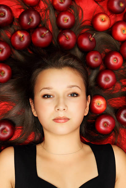 beauty lying on apples Beautiful woman lying on a red fabric with apples plus size smart casual dresses stock pictures, royalty-free photos & images