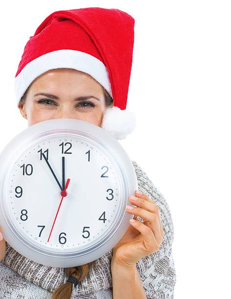 istock Smiling young woman in christmas hat hiding behind clock 461066129