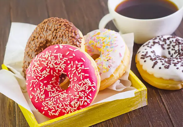 Photo of Four sprinkle donuts and a cup of coffee