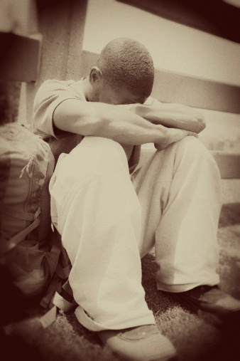 Depressed, homeless man sits in a park in Santa Monica, California. Sepia toned.