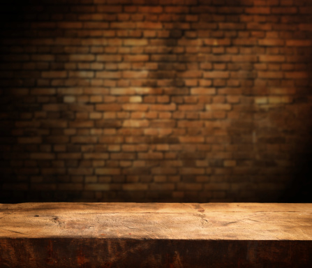 Empty wooden table and brick wall in background