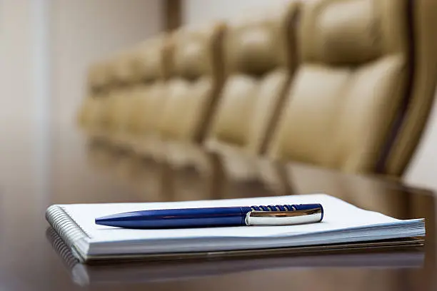 Closeup of notepad kept on table in empty conference room