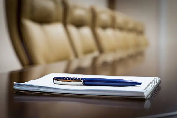 Closeup of notepad kept on table in empty conference room