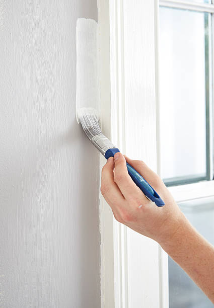 istock Male painting wall next to window 461093441