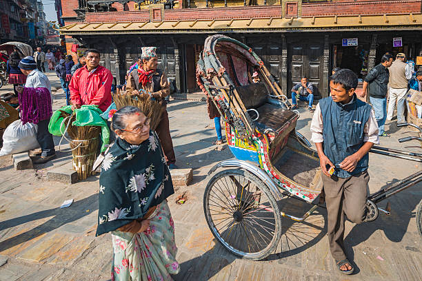 Kathmandu rickshaw driver market traders in crowded Thamel Nepal Kathmandu, Nepal - 9th November 2012: Tricycle rickshaw driver and broom salesmen waiting for customers in the crowded streets of Thamel, in the heart of Kathmandu, Nepal's vibrant capital city. thamel stock pictures, royalty-free photos & images