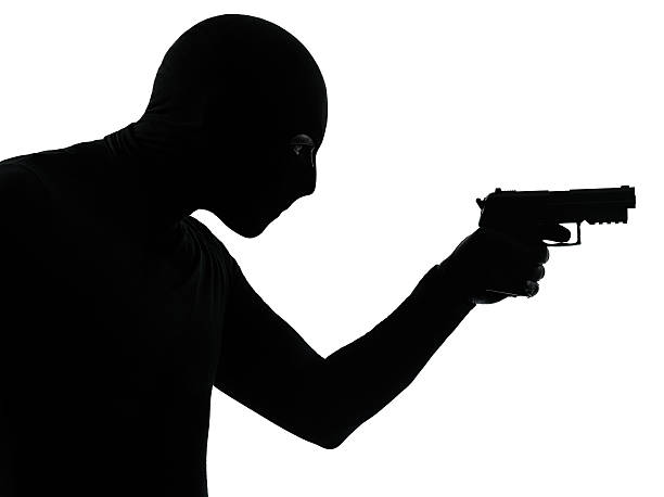 istock thief criminal terrorist aiming gun man silhouette 461112817