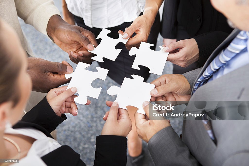 Businesspeople Holding Jigsaw Puzzle Close-up Photo Of Businesspeople Holding Jigsaw Puzzle Above Stock Photo