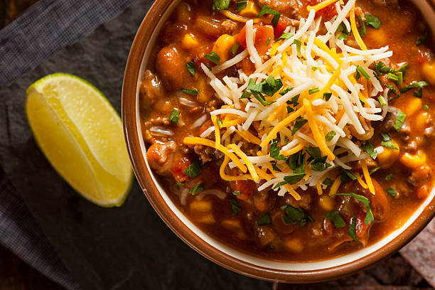 Bowl of homemade chili topped with cheese and slice of lemon Soutwestern Santa Fe Soup with Beans Corn and Cheese chili con carne photos stock pictures, royalty-free photos & images