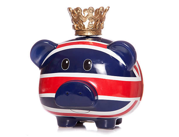 british piggy bank vestindo uma coroa - piggy bank gold british currency pound symbol - fotografias e filmes do acervo