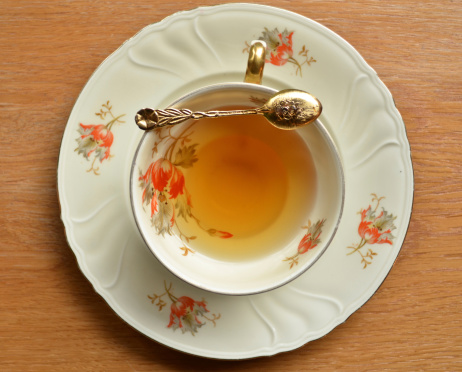 Cup of tea and teaspoon on wooden
