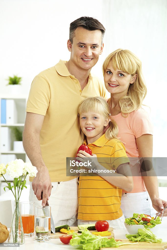 Family in the kitchen Portrait of happy parents and their daughter looking at camera in the kitchen Adult Stock Photo