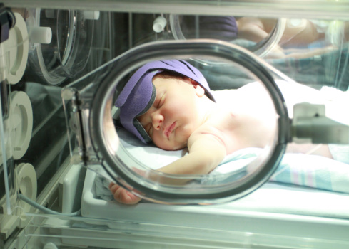 Portrait of a newborn baby with jaundice in a hospital under lights