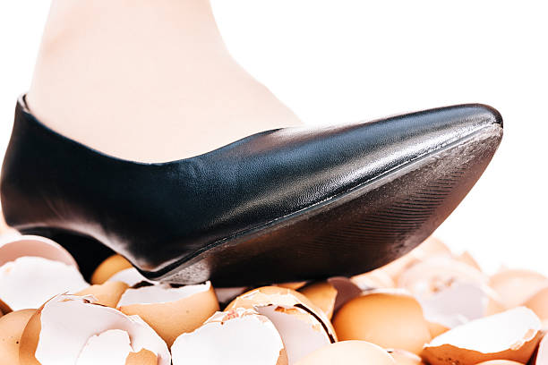 Walking on eggshells Walking on eggshells metaphor showing close-up of female lower leg above broken eggshells. animal egg walking on eggshells walking broken stock pictures, royalty-free photos & images