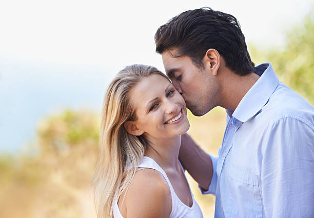 Shot of an attractive young man giving his girlfriend a kiss on the cheek as they stand outside