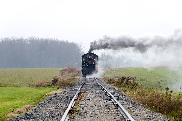 Steam Locomotive Coming Down the Track Direct view of a steam train locomotive approaching down the track on a winter day. Hint of snow in the air. road going steam engine stock pictures, royalty-free photos & images